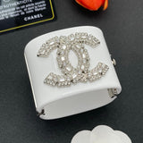 White jewelry box with Chanel logo embellished with crystals on a dark surface.