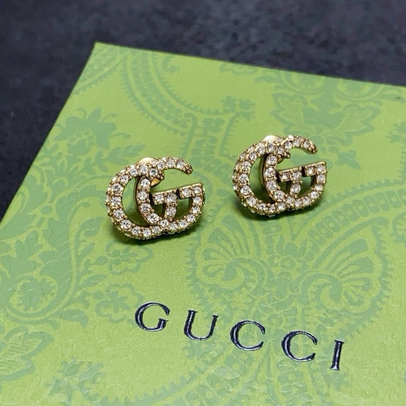 Gold Gucci earrings on a green Gucci card