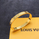 Gold bracelet on a Louis Vuitton box with a dark textured background